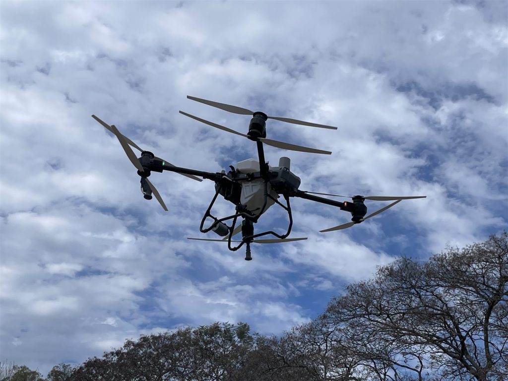 农用无人机在空中作业,机身下方是药箱与喷头